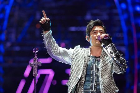 Jay Chou in a silver jacket singing a song.